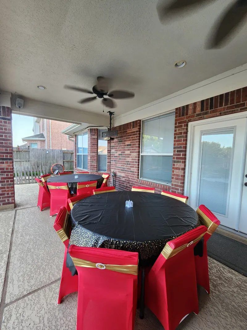 Round tables with black covers and red chair covers on a covered patio